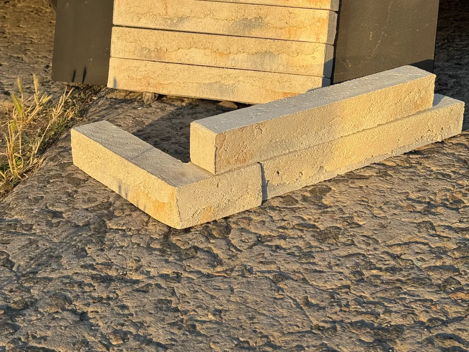 Кутовий елемент і рядові вироби GoodBrick ручної формовки на землі, видно товщину